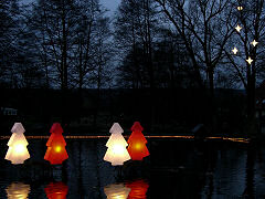 Foto: zwei weiße und zwei rote Weihnachtsbäume auf dem Dorfteich